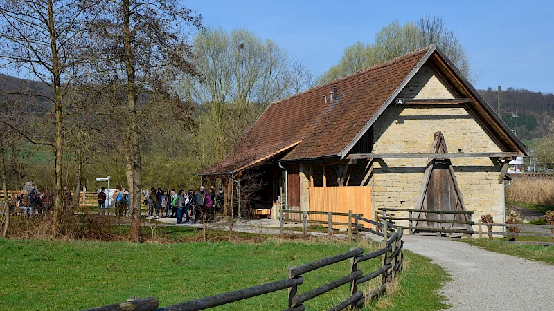 Im Hintergrund eine kleine Gruppe vom Menschen vor einem alten Haus.
