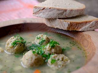 Germknödel in einer Holzschüssel mit zwei dicken Scheiben Brot auf dem Rand.