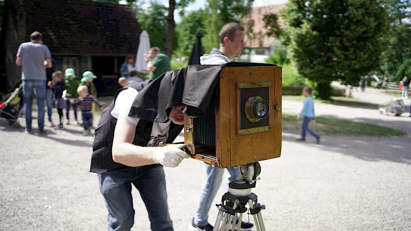 Mann unter dem Tuch einer historischen Fotokamera auf einem Stativ