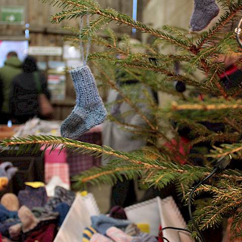 Kleine gestrickte Sockenanhänger an einem Tannenbaum